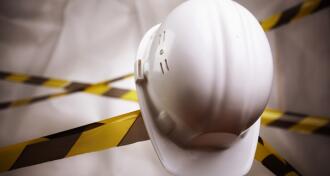 White construction hat sitting on tool with black and yellow tape in backgroun