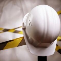 White construction hat sitting on tool with black and yellow tape in backgroun