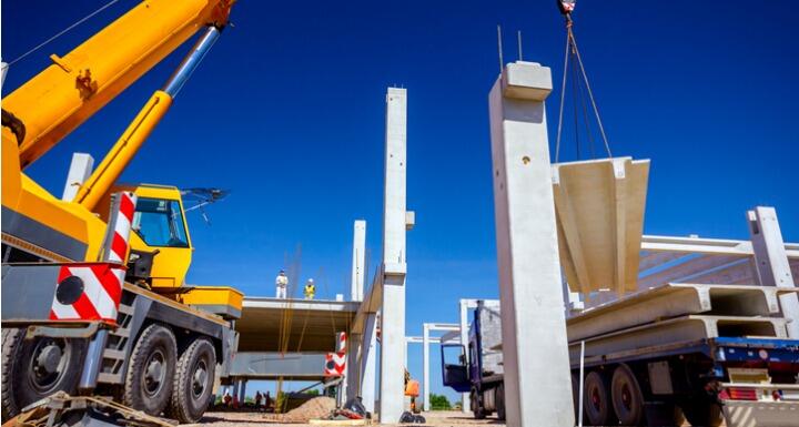 Unloading concrete pillar from truck trailer at construction site 