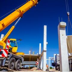 Unloading concrete pillar from truck trailer at construction site 