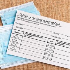 Image of a vaccine card on top of a facemask
