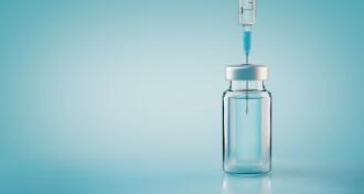 Vaccine bottle with needle on blue background