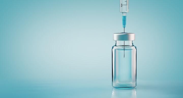 Vaccine bottle with needle on blue background