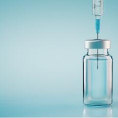 Vaccine bottle with needle on blue background