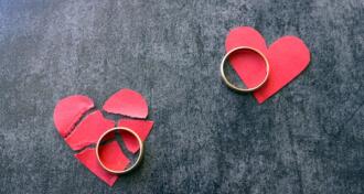 Two wedding rings on torn paper broken red hearts