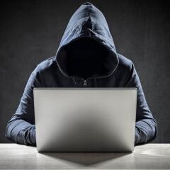 hooded figure using laptop