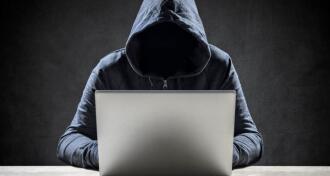 hooded figure using laptop