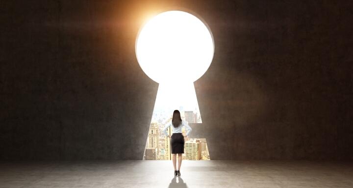 Silhouette of a woman standing in front of an oversized keyhole