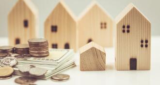 Multiple wooden homes with a stack of money