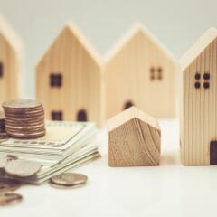 Multiple wooden homes with a stack of money