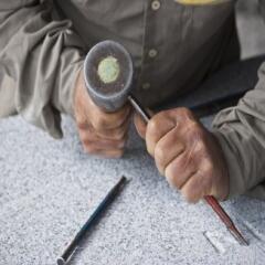 A stonemason working on granite with a chisel