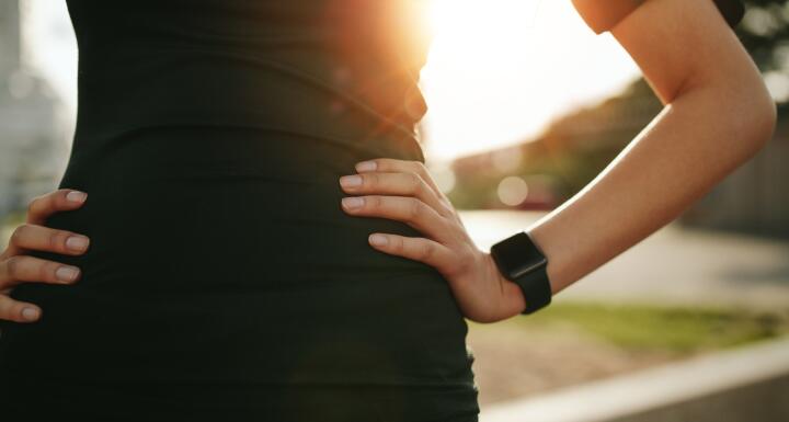 Torso of woman with hand on hip wearing a smartwatch