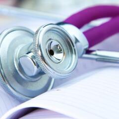 A stethoscope with a purple earpiece on a white lab coat