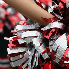 Cheerleader hand holding a red silver and black pom pom behind their back