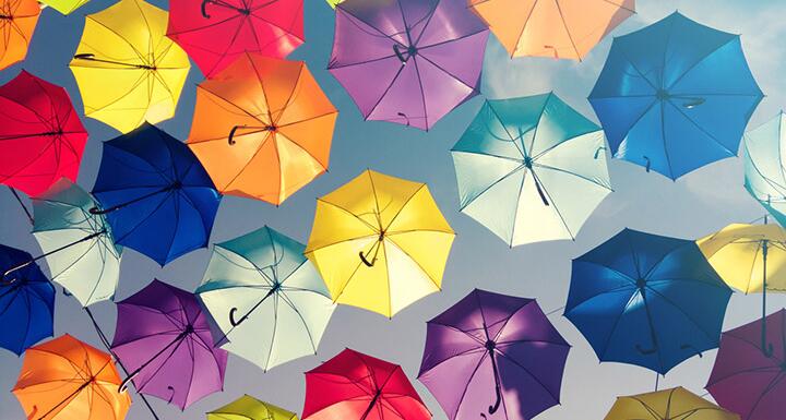 Looking up in the sky at the underside of umbrellas colored yellow red blue purple and orange