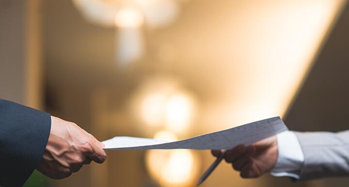 man handing sheet of paper to another person