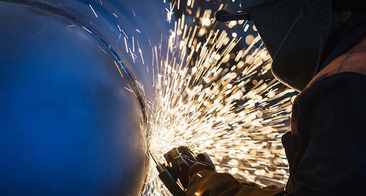 A welder cuts steel and sparks fly