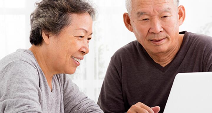 Elderly woman and elderly man looking at laptop screen