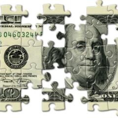 One hundred dollar bill cut into puzzle pieces with several of the pieces missing