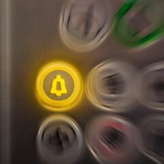 An alarm button lit in yellow in an elevator