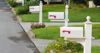 Row of three white mailboxes and neatly trimmed lawns to illustrate restrictive covenants