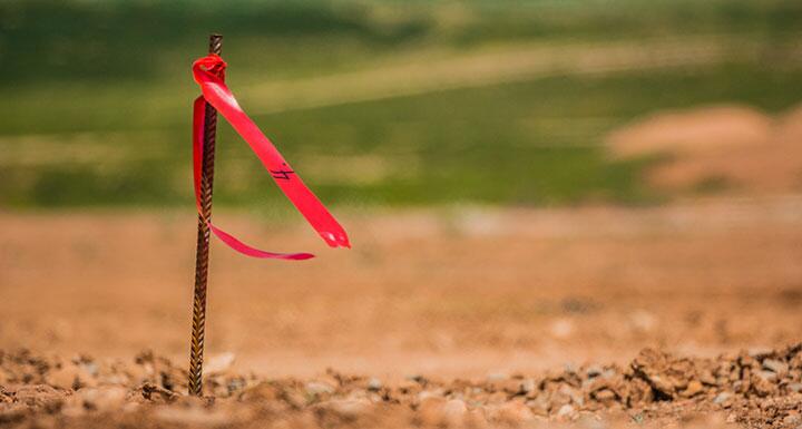 A surveyor's stake with a red flag in a plot of cleared land