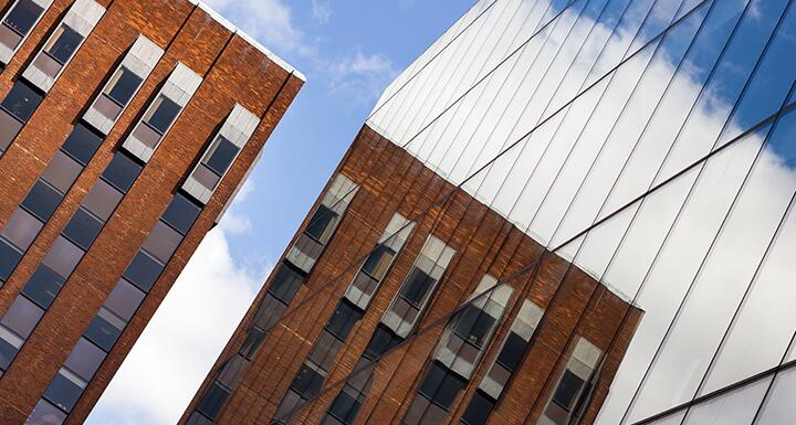 A Brick building reflected in the windows of a commercial building