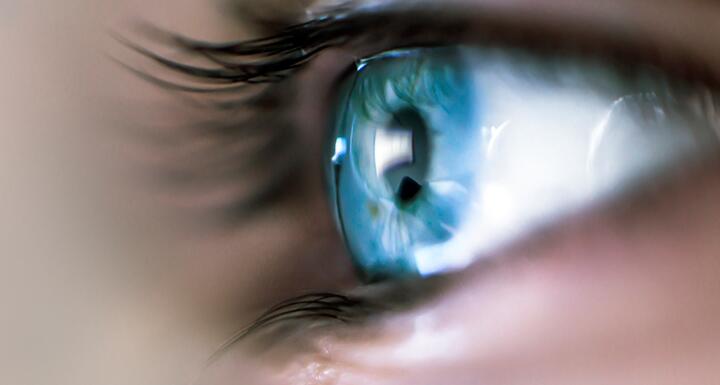 Close up picture of a person's bright blue eye with long eyelashes
