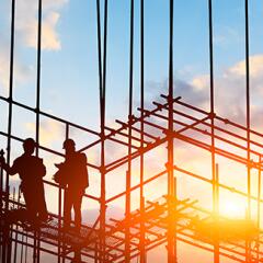 Construction workers on scaffolding with a sunset in the background