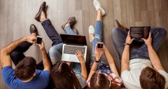 Four young adults working on devices
