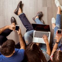 Four young adults working on devices