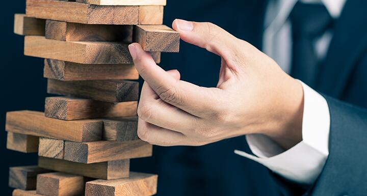 Hand pulling out wooden block from Jenga tower