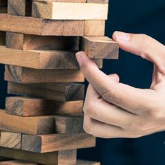 Hand pulling out wooden block from Jenga tower