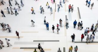 View from above looking down on a crowd of people walking around on a white floor