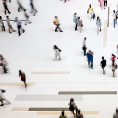 View from above looking down on a crowd of people walking around on a white floor
