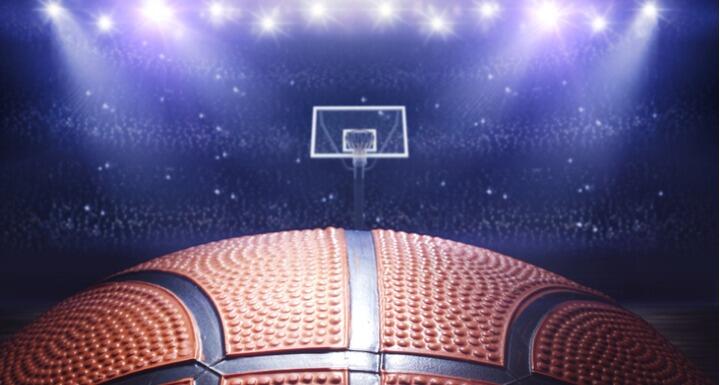 Close up on basketball with basketball hoop in arena