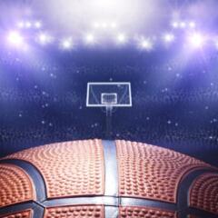 Close up on basketball with basketball hoop in arena