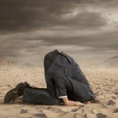 businessman hiding head in the sand