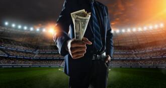 businessman holding handful of money at soccer stadium