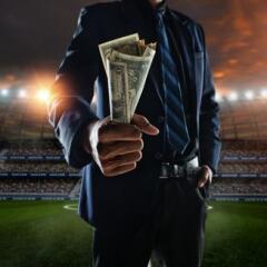 businessman holding handful of money at soccer stadium