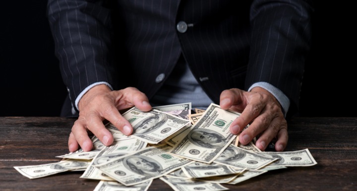 Man in Suit sweeping money into his hands