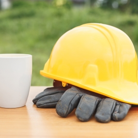 Construction Hat, Gloves, and cup on wood table