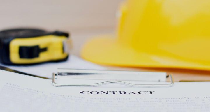 Yellow Hard Hat and Construction Contract representing Why Notice and Opportunity to Cure Matter in Construction Contracts