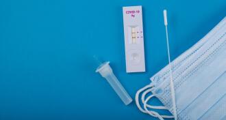 An unwrapped home covid test on a blue background
