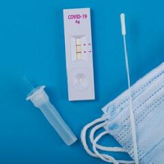 An unwrapped home covid test on a blue background