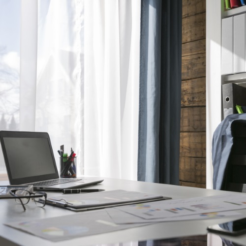 Home office with desk, laptop, and glasses