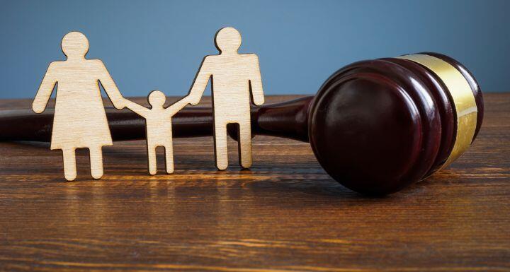 Wood cutout of mom, child, and dad figure in front of a gavel