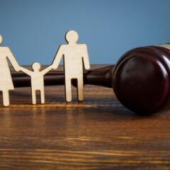 Wood cutout of mom, child, and dad figure in front of a gavel