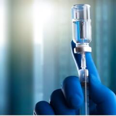 gloved hand holding vaccine and syringe