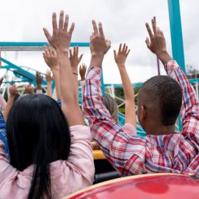 People riding coast with their hands up. 